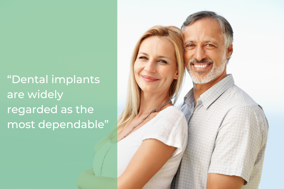 Smiling middle-aged couple stands together beside a green panel displaying the text, “Dental implants are widely regarded as the most dependable tooth replacement.”.